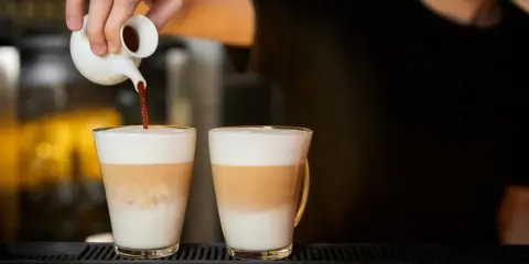 Barista wlewa espresso do dwóch latte macchiato. Zastanawiasz się, ile kcal ma latte macchiato?