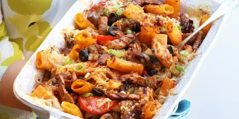 Pyszna zapiekanka z mięsem mielonym, makaronem rigatoni, oliwkami i pomidorami, posypana serem i szczypiorkiem.