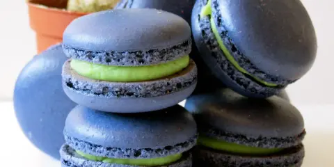 Macarons bleus avec une garniture verte vibrante, parfaits pour une recette macaron pistache.