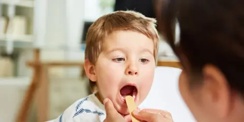 Bambino con bocca aperta durante visita medica per sospetta laringite.