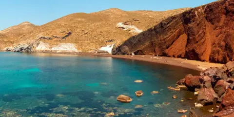 Santorini plaże: Czerwona plaża z turkusową wodą i skalistymi klifami.