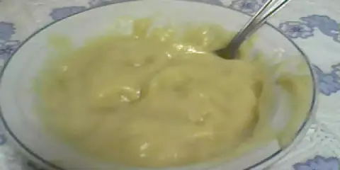 Un tazón blanco con un suave y cremoso puré de pescado, listo para ser disfrutado. Una cuchara plateada descansa en el tazón.
