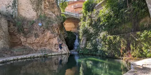 Un hombre posa junto a una cascada en un estanque natural en Ferez, Albacete.