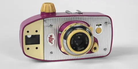 Uroczy, różowo-żółty polski aparat fotograficzny sprzed lat, z napisem "Alfa" i obiektywem Euktar.