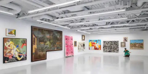 A vibrant art exhibition at Saatchi Yates, featuring diverse paintings and a sculpture, with a striking pink artwork and a figure in a colorful dress.