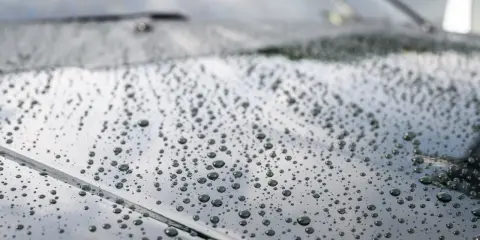 Krople wody na ciemnym lakierze po nałożeniu ceramiki. Efekt perlenia świadczy o hydrofobowości powłoki.