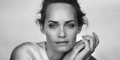 Ritratto in bianco e nero di una donna con mani appoggiate al viso, un'espressione intensa catturata da un fotografo ritrattista famoso.