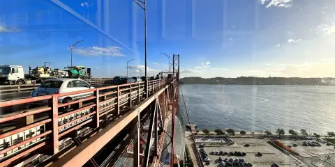 Autobahnverkehr auf der Brücke in Lissabon, mit Blick auf den Tejo und einen Parkplatz neben Pilar 7.