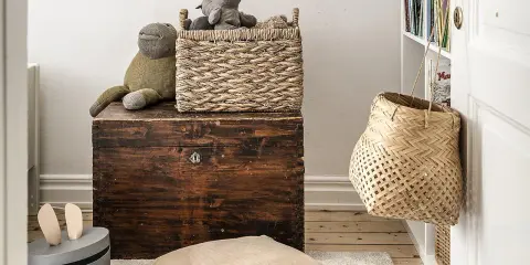 Cesti di vimini per idee arredare con stile: un cesto intrecciato sopra un baule antico, un altro appeso alla porta.