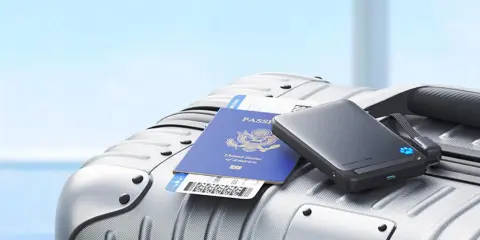 En powerbank, pass och flygbiljett ligger på en resväska, redo för resan med flygplan.