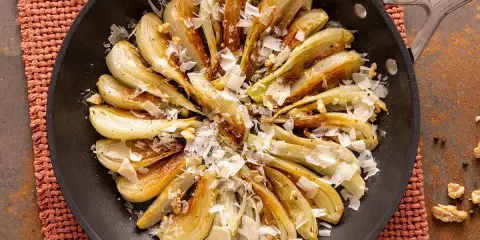 Finoçchi gratinati in padella, dorati e saporiti, guarniti con scaglie di formaggio e noci croccanti.