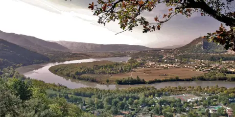 Vue panoramique d'une vallée avec une rivière sinueuse, des vignobles et un village. Idéal pour une randonnée à Pertuis.