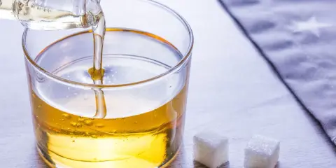 Versez le sirop de glucose dans un bol. Une recette simple pour des desserts parfaits. Trois morceaux de sucre à côté.
