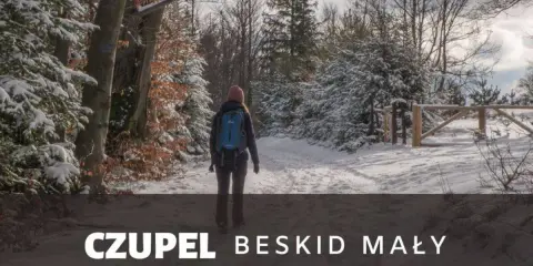 Kobieta w zimowej czapce i plecaku idzie zasypaną śniegiem trasą na Czupeł w Beskidzie Małym.