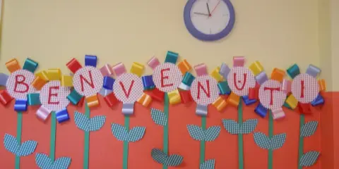 Fiori colorati con lettere formano la scritta "BENVENUTI", un'idea creativa per lavoretti di accoglienza.