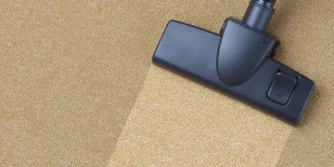 Cabezal de aspiradora limpiando una alfombra beige. El proceso de como limpiar una alfombra es sencillo con esta herramienta.