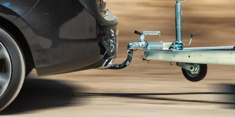 Czarne auto z przyczepą, widoczny hak holowniczy.