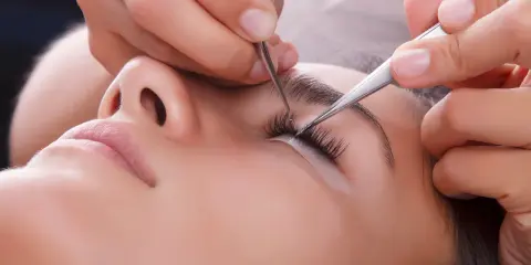 Pose de cils pour un rehaussement cil et teinture. Une esthéticienne applique des extensions avec précision.