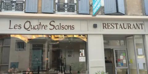 Le restaurant étoilé Les Quatre Saisons à Aurillac, une façade accueillante avec une enseigne lumineuse.