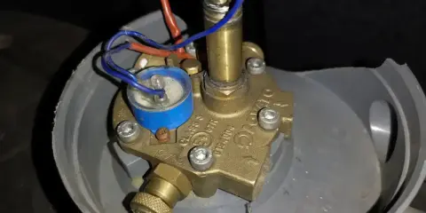 Uszkodzony elektrozawór LPG. Widoczne luźne przewody i korozja, potencjalne objawy awarii.