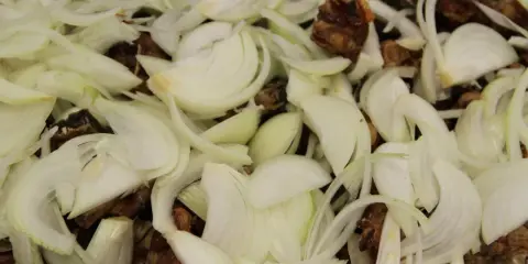 Oignons émincés et morceaux de viande brune, prêts à mijoter pour un délicieux jus de veau.