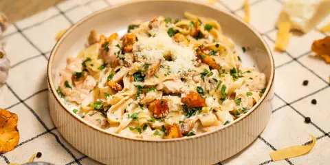 Pyszny makaron w sosie kurkowym z kawałkami kurczaka i posypany parmezanem.