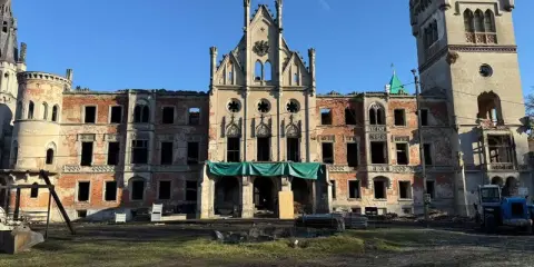 Ruiny pałacu w Kopicach, zniszczony zamek z ceglanymi ścianami i pustymi oknami, pod błękitnym niebem.