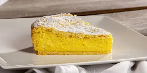 Una fetta di crostata di ricotta, con la sua base dorata e il ripieno cremoso, spolverata di zucchero a velo.