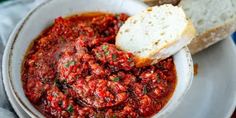 Schüssel mit würzigem Acili Ezme, einem scharfen türkischen Dip aus Tomaten und Paprika, serviert mit frischem Brot.