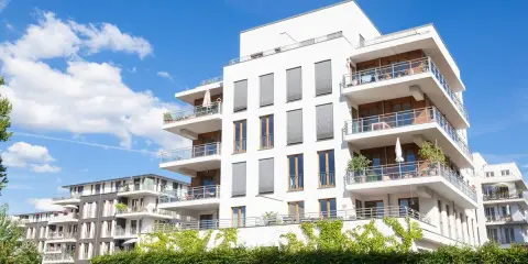 Immeubles modernes avec balcons fleuris, sous un ciel bleu. Un projet immobilier qui pourrait bénéficier de la loi Borloo pour son accessibilité.