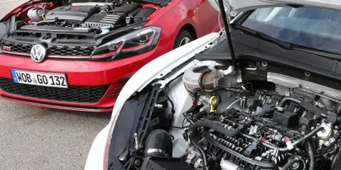 Dos Volkswagen Golf 7 GTI, uno rojo y otro blanco, con capós abiertos mostrando sus motores.