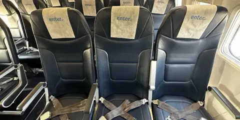 Puste, ciemne fotele w samolocie Enter Air z pasami bezpieczeństwa.
