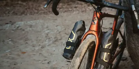 Dwie czarne torby podsiodłowe z żółtym wzorem zamontowane na ramie roweru gravelowego.