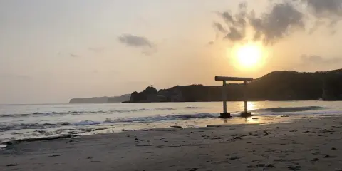 Zachód słońca nad spokojnym morzem, z bramą torii na plaży w Japonii.