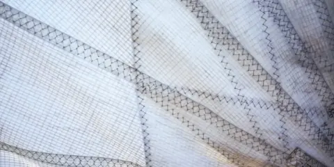 Nahaufnahme eines weißen Segels mit sichtbaren Nähten und Gittermuster. Das Segel reinigen ist wichtig für die Langlebigkeit.