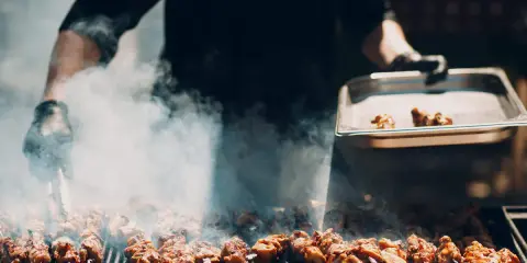 Un chef prépare un délicieux barbecue italien, des brochettes de viande fumantes sur le grill.