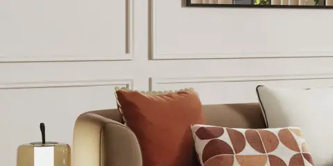 Cojines decorativos de sofá en tonos tierra y un diseño geométrico, junto a una lámpara.