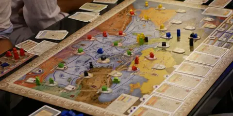 Intensywne granie w gry planszowe. Gracze strategicznie rozmieszczają drewniane pionki na mapie, budując imperium.