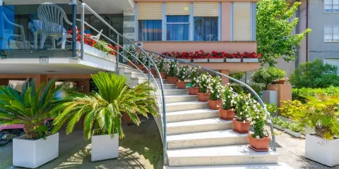 L'ingresso fiorito del hotel dell'amarissimo, con scale bianche ornate da piante e fiori, invita ad entrare.