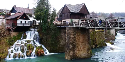 Rastoke, Croazia: cascate e mulini sull'acqua. Un ponte metallico attraversa il fiume, collegando case tradizionali.