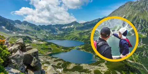 Ojciec i dziecko na szlaku w Dolinie 5 Stawów. Chłopiec wskazuje na jezioro, podziwiając górski krajobraz.