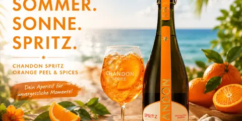 Sommer, Sonne, Spritz! Ein Glas Chandon Spritz mit Orangenscheibe und Eis steht neben der Flasche am Strand. Perfekt für unvergessliche Momente.