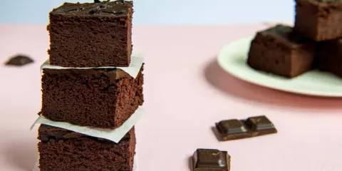 Ciemne, wilgotne brownie z fasoli ułożone w stosik, obok kawałki czekolady.