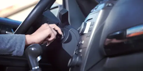 Mano girando la llave de contacto. Es malo tener el coche arrancado mucho tiempo, consume combustible y contamina.