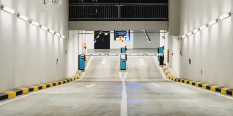 Einfahrt in eine Tiefgarage mit Schranken und Pfeilen, die den Weg weisen. Effizientes Parkraummanagement sorgt für Ordnung.