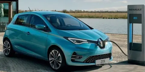Renault Zoe, una delle auto elettriche più vendute, in carica vicino a un lago.