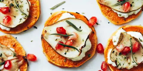 Deliciosas rodajas de boniato asado con queso cremoso, pera, granada y romero. Ideales para recetas con boniato.