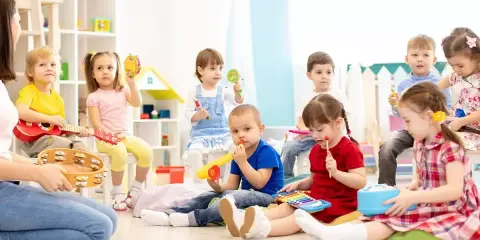 Wesołe zabawy w przedszkolu: dzieci grają na instrumentach, śpiewają i bawią się w rytm muzyki.