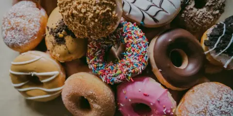 Kolorowe pączki z posypką, lukrem i cukrem pudrem. Zastanawiasz się, ile kalorii ma pączek?