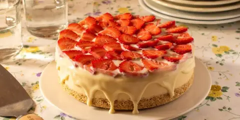 Deliciosa tarta de frutas cubierta de fresas frescas y glaseado blanco cremoso.